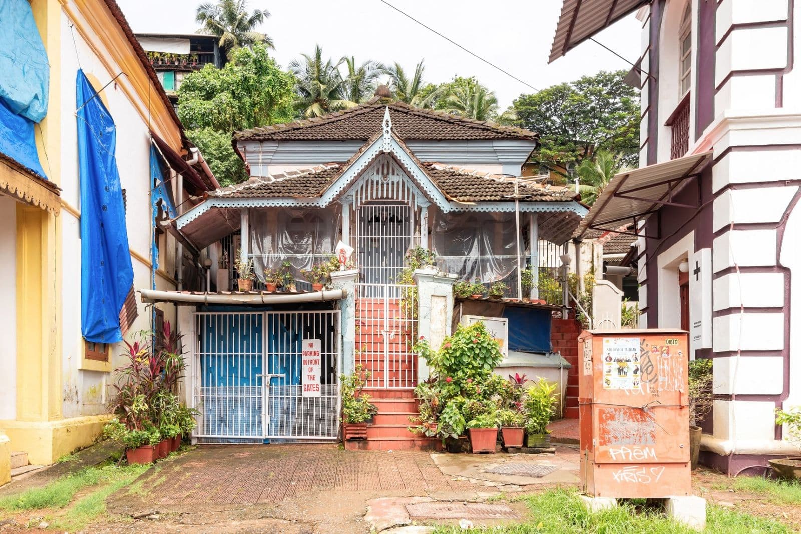 A Portuguese-era house with a carved balcony and potted plants on a Fontainhas street