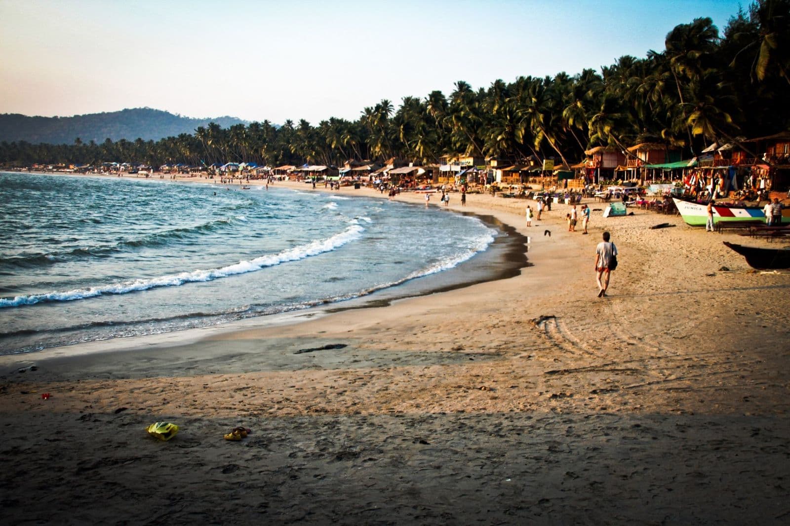 The crescent of Palolem beach lined with coconut palms, with waves breaking on the sand