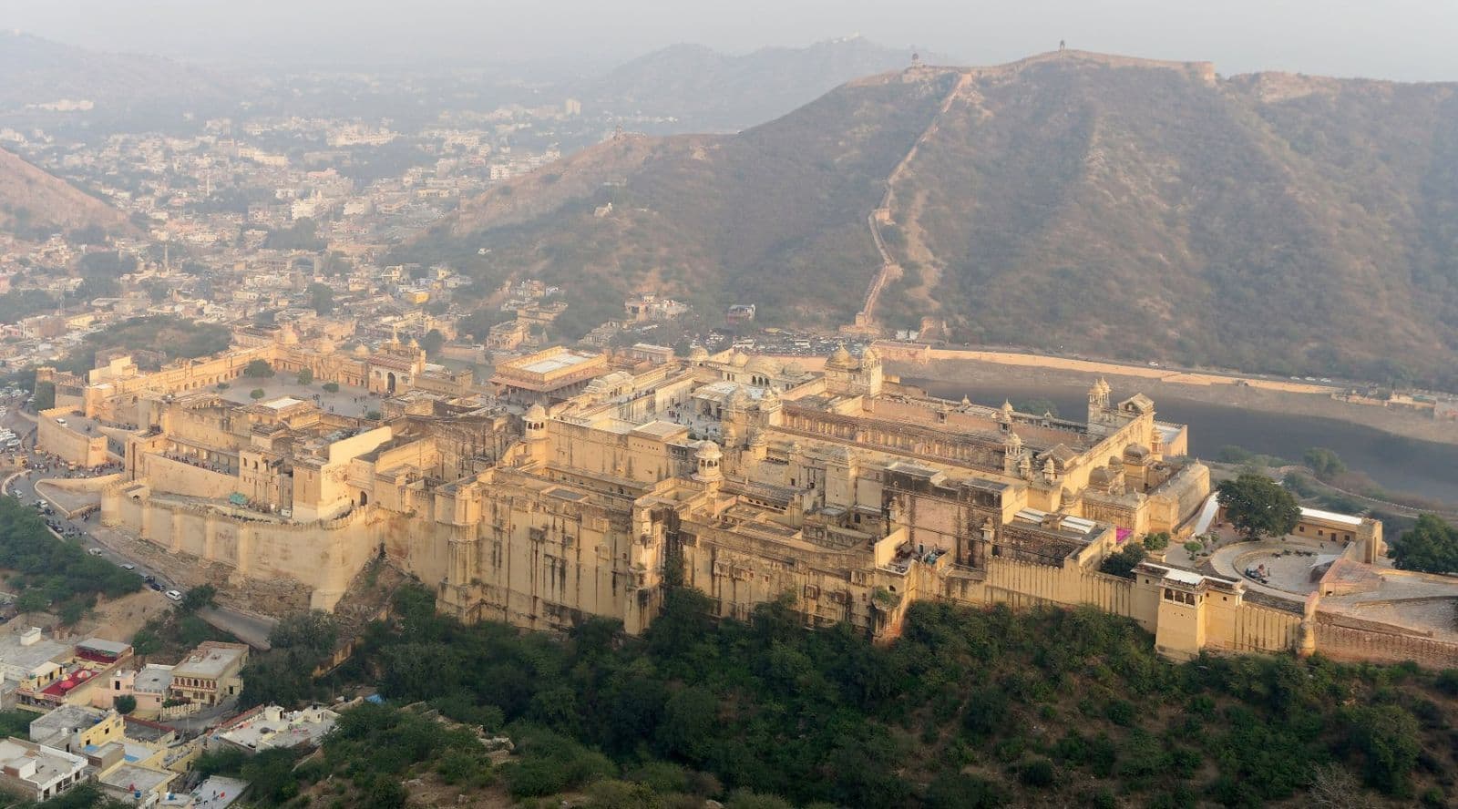 Amber Fort's honey-coloured walls and palaces spread along a hillside, seen from above