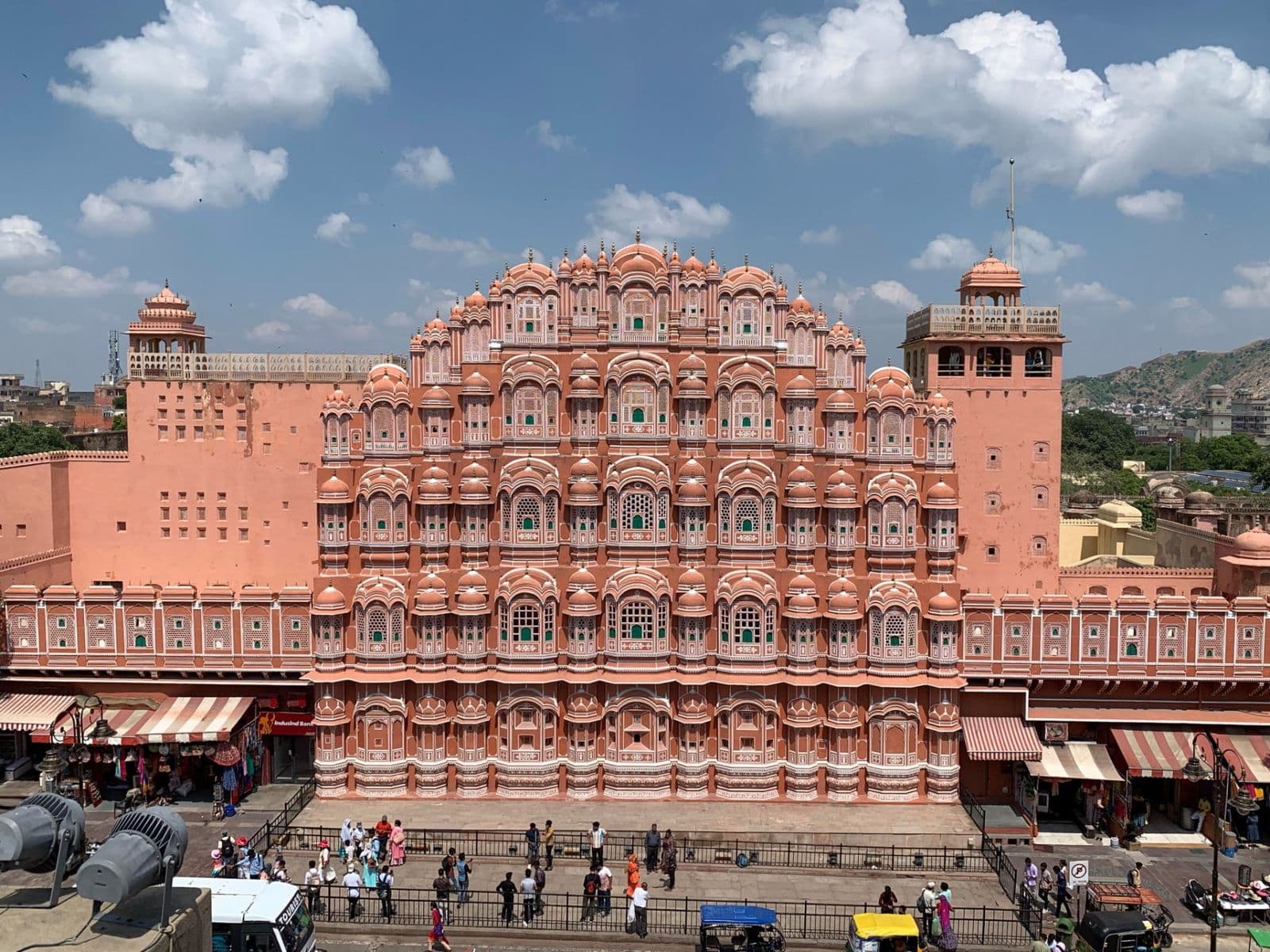 The pink sandstone honeycomb facade of Hawa Mahal against a blue sky with clouds