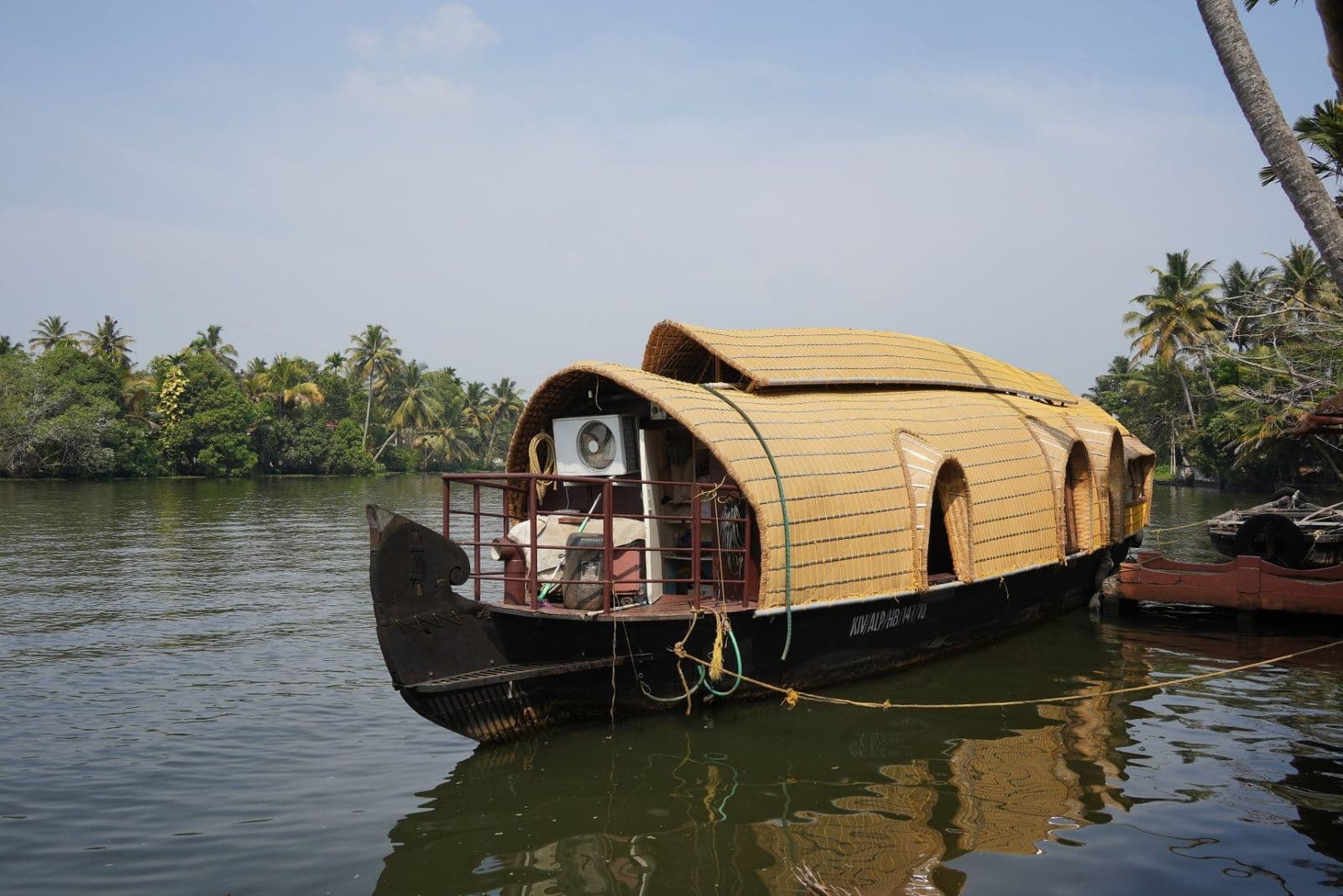A cane-roofed kettuvallam houseboat moored on the palm-fringed Kerala backwaters