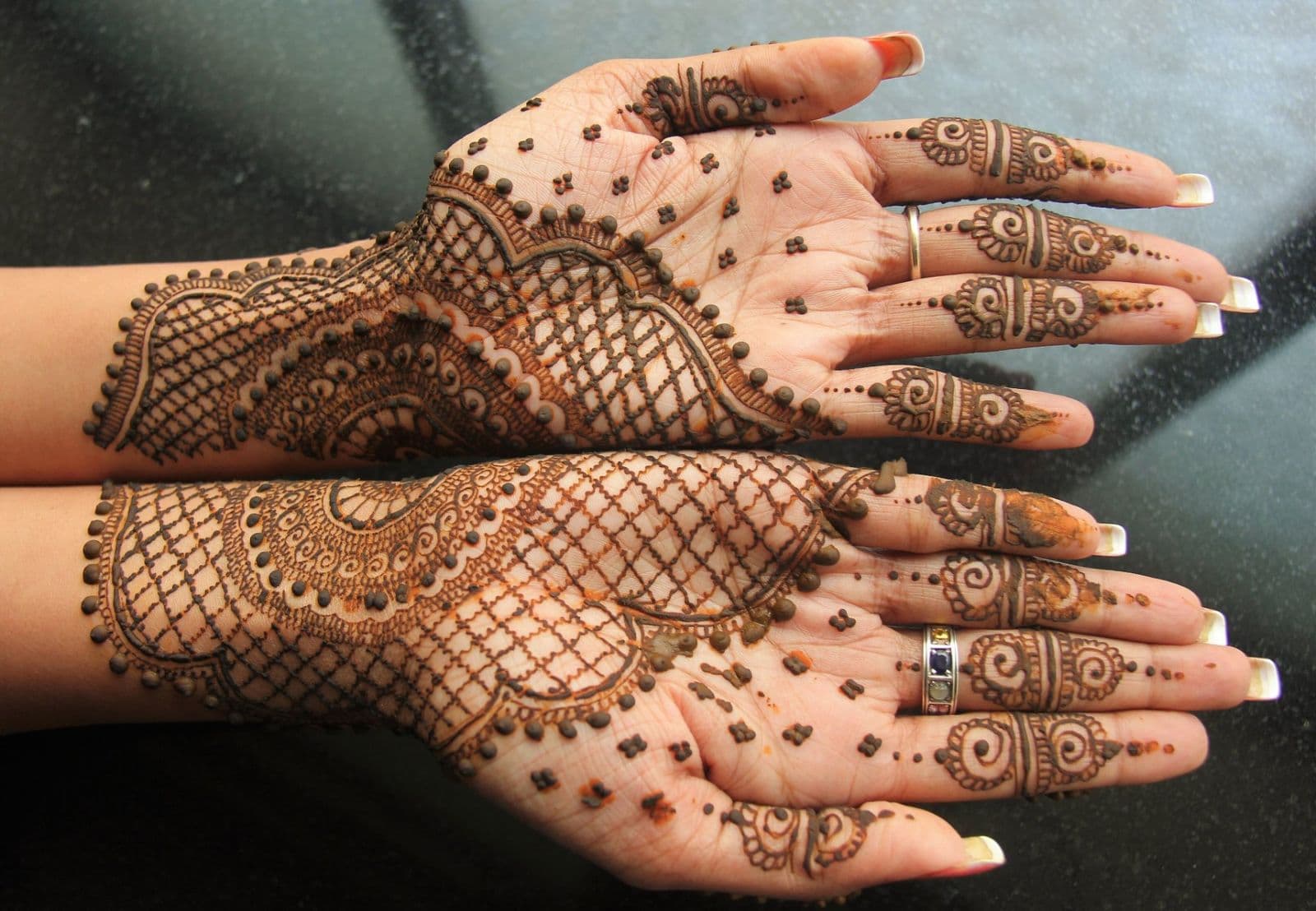 Both palms decorated with intricate brown henna patterns