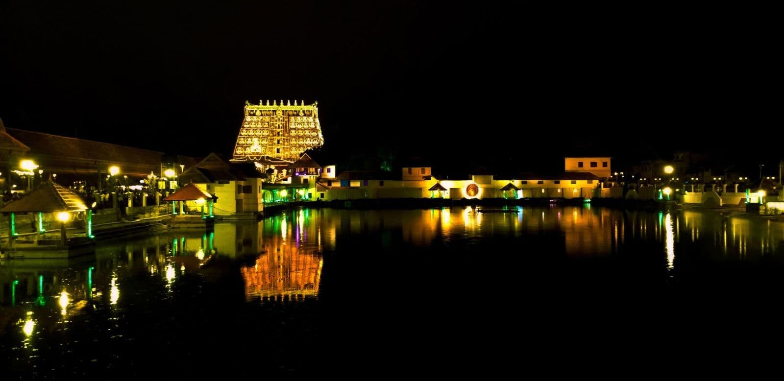 Sree Padmanabhaswamy Temple lit with lamps at night, reflected in the temple tank