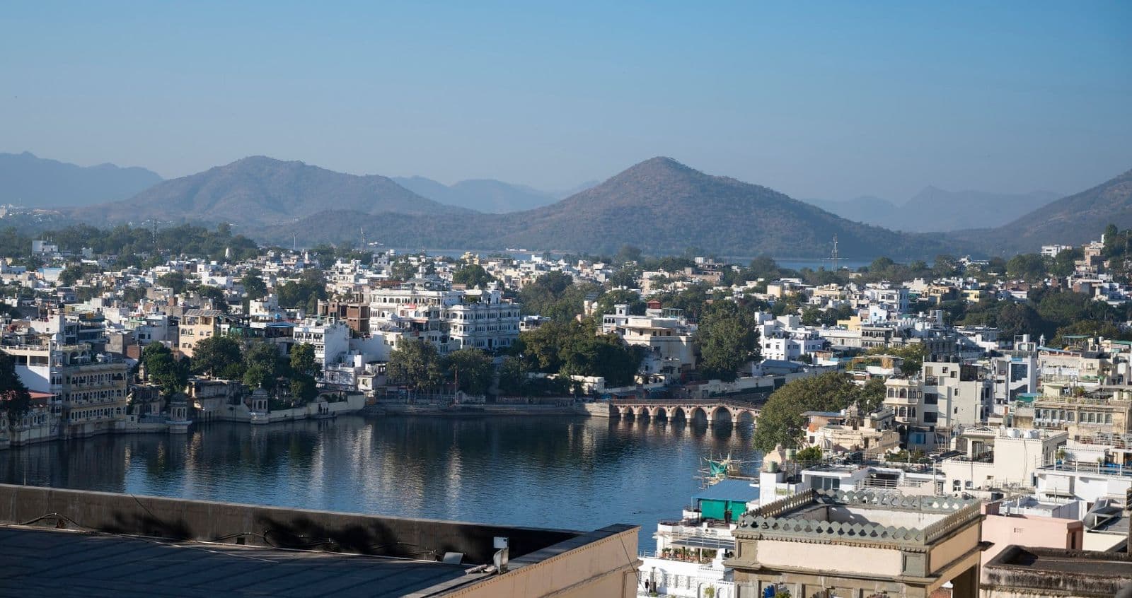 Udaipur's white houses and lake with the Aravalli hills beyond, seen from the City Palace
