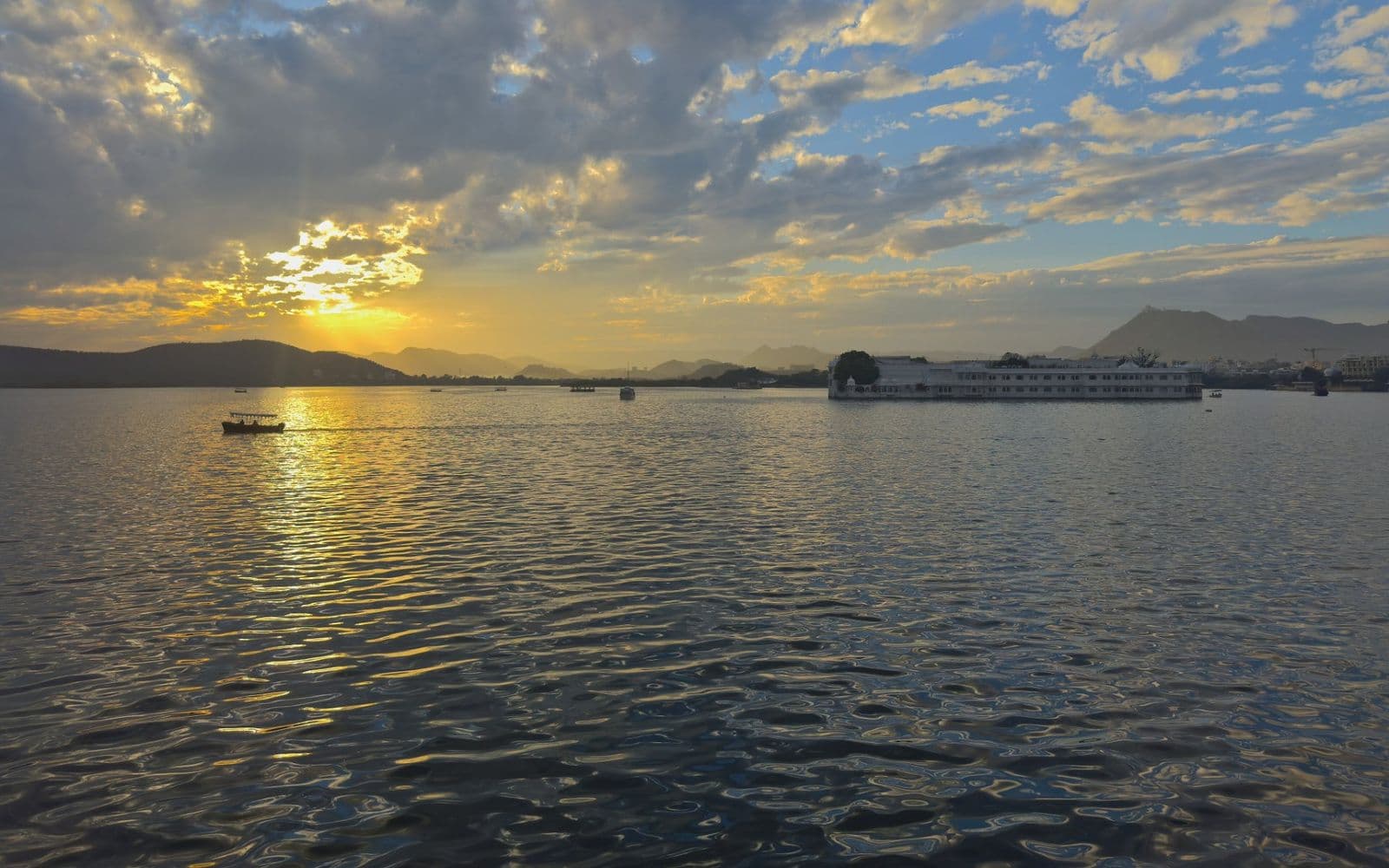 The sun setting over Lake Pichola, with hills on the horizon