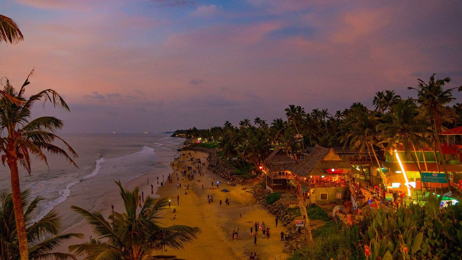 The lights of Varkala's clifftop cafés glowing above the beach at dusk